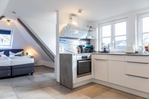 a kitchen with white cabinets and a bed in a room at living TIMELESS - Apartments zum roten Lamm- Bad Krozingen in Bad Krozingen