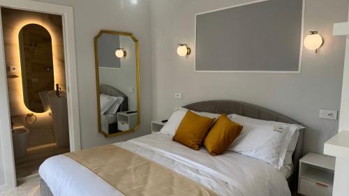 a bedroom with a bed with two pillows and a mirror at AC GOLD B&B Boutique Rooms & Suite in Reggio Calabria
