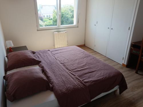 a bedroom with a brown bed with a window at La perle de Châteauneuf in Châteauneuf-du-Faou