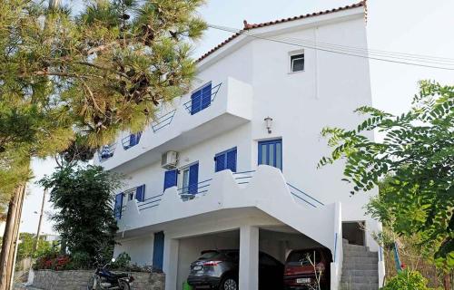 een wit huis met een auto ervoor geparkeerd bij Haris Apartments in Armenistis