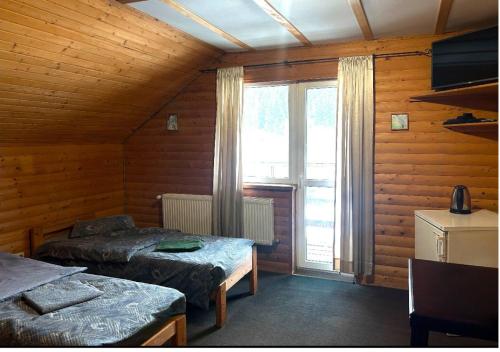 a bedroom with two beds and a large window at Готель Могул in Vorokhta