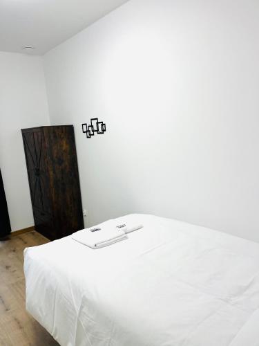 a bedroom with a white bed with white sheets at Apartamenty przy Muzeum in Brzeziny