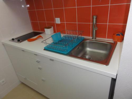 a kitchen counter with a sink and red tiles at Pedras Del Rei Studio in Tavira