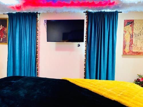 a bedroom with blue and yellow curtains and a tv at Sweet Home Georgia Enchanté in Norcross
