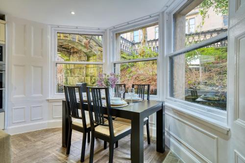 a dining room with a table and chairs and large windows at Stylish 3-Bedroom Apartment in Central Glasgow in Glasgow