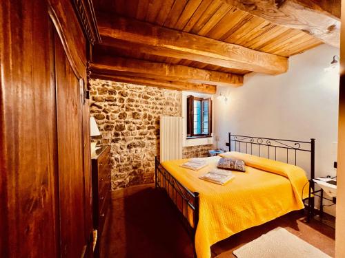 a bedroom with a yellow bed in a stone building at Agriturismo Montagna Verde Apella in Licciana Nardi