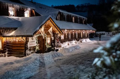 a log cabin covered in christmas lights in the snow at Czarna Owca in Istebna