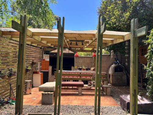 a wooden pergola with a picnic table and a bench at Algarrobo Lodge in Algarrobo