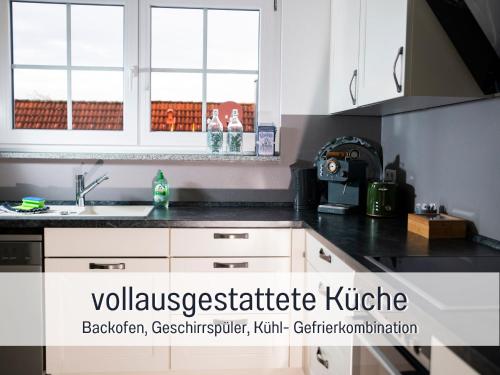 a kitchen with white cabinets and a black counter top at Gemütlich*Stylisch*Netflix*Blick ins Grüne* in Lindau