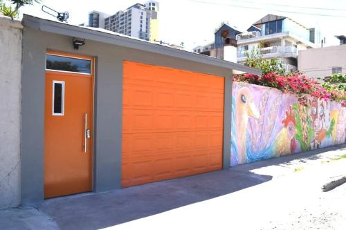 an orange garage door in front of a wall with a mural at Edgy Vibes Studio in Tijuana in Tijuana