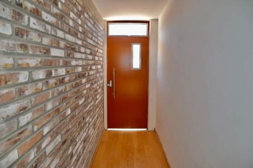 a hallway with a brick wall and a red door at Edgy Vibes Studio in Tijuana in Tijuana