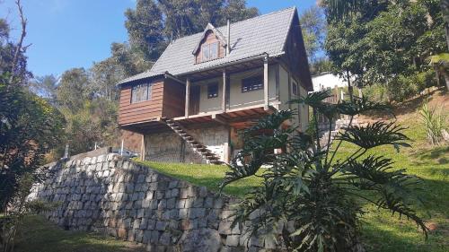 a wooden house on top of a stone wall at Cottage in Penedo! in Itatiaia