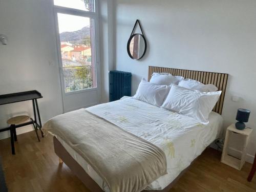 une chambre avec un lit avec des draps blancs et une fenêtre dans l'établissement Appartement cosy dans une maison de caractère, à Tallard