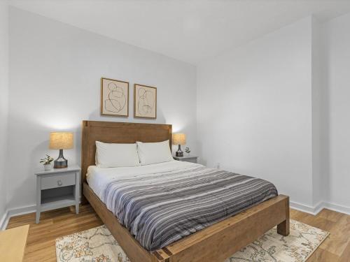 a bedroom with a bed with two tables and two pictures on the wall at Lawrenceville Central !2 Stylish and Quiet One Bedroom Apartment with Free Street Parking in Pittsburgh