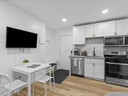 a kitchen with white cabinets and a table and a tv at Lawrenceville Central !2 Stylish and Quiet One Bedroom Apartment with Free Street Parking in Pittsburgh