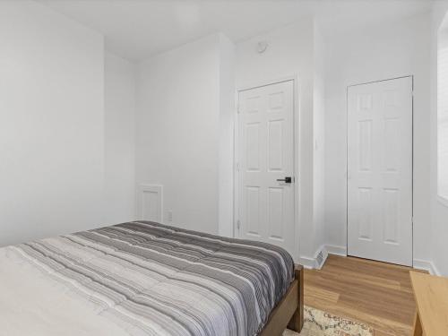 a bedroom with white walls and two white doors at Lawrenceville Central !2 Stylish and Quiet One Bedroom Apartment with Free Street Parking in Pittsburgh