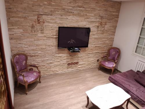 a living room with a flat screen tv on a brick wall at Ayoub Jus Station métro de Cité el Khadra in Tunis