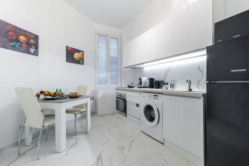une cuisine blanche avec une table et une machine à laver dans l'établissement Cosy Studio, close to Monaco Train Station, à Beausoleil