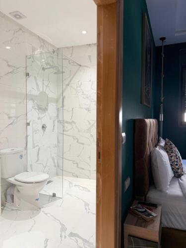 a bathroom with a toilet and a glass shower at Playa Surf House in Tamraght Ouzdar