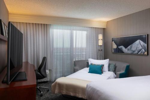 a hotel room with a bed and a desk and a television at Courtyard by Marriott Denver Airport in Denver