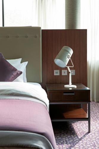 a lamp on a table next to a bed at The Glasshouse, Autograph Collection in Edinburgh