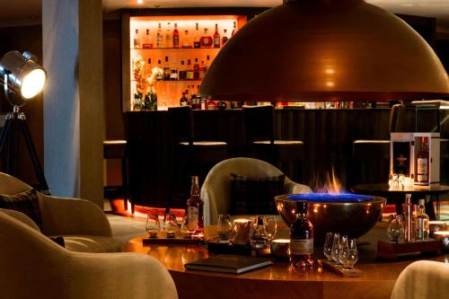 a bar with a table with bottles of alcohol on it at The Glasshouse, Autograph Collection in Edinburgh