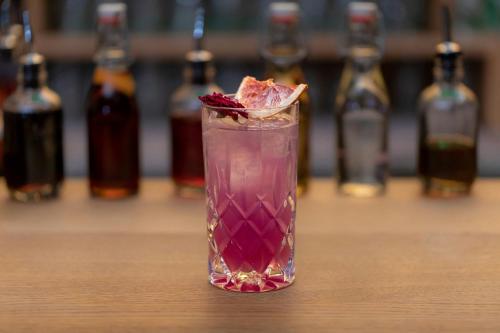 a pink cocktail sitting on a table with bottles in the background at LUME Boutique Hotel, Autograph Collection in Frankfurt/Main