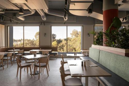 a restaurant with tables and chairs and large windows at Courtyard by Marriott Perth Murdoch in Fremantle