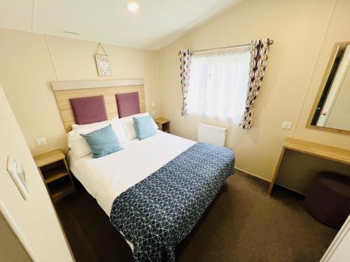 a bedroom with a bed with a blue blanket and a window at 3 Bedroom Caravan OG35, Lower Hyde, Shanklin in Shanklin