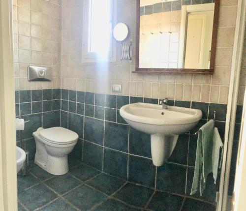 a bathroom with a sink and a toilet and a mirror at Villa Mare Azzurro, 2 passi dal mare in Simius