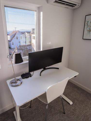 a white desk with a computer on it in front of a window at Steps to Alki Beach with Water Views Rooftop deck in Seattle