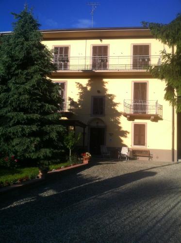 a large white building with a tree in front of it at B&B Cantine Pietronero in Orsara Bormida