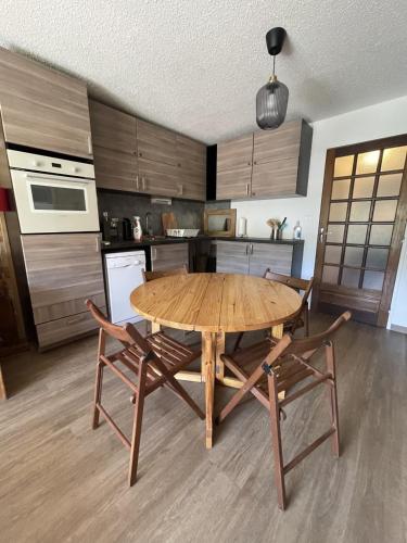 une cuisine avec une table en bois et deux chaises dans l'établissement Superbe appartement 5 à 6 couchages front de neige Risoul, à Risoul