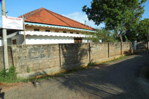 a brick retaining wall next to a building with a fence at Flamingo Resort in Mannar