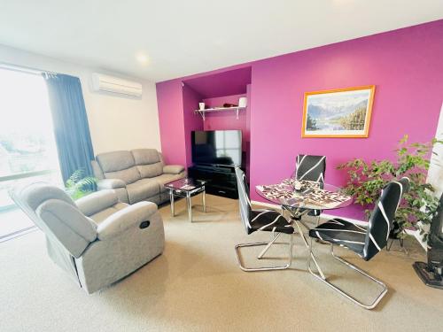クライストチャーチにあるCity Fringe Private Room - Your Urban Escape!の紫の壁のリビングルーム(ソファ、テーブル付)