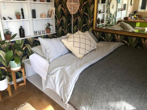 a bed with pillows on it in a room with plants at Raglan LoveNest -Romantic escape with outdoor bath in Raglan