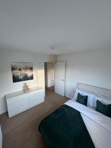 a bedroom with a large bed with a green blanket at Modern & Spacious 3-Bedroom Home in Dartford, Ideal for Families, Groups and Contractors in Dartford