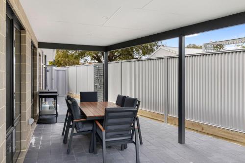 a patio with a wooden table and chairs at Saltwater Lane in Busselton