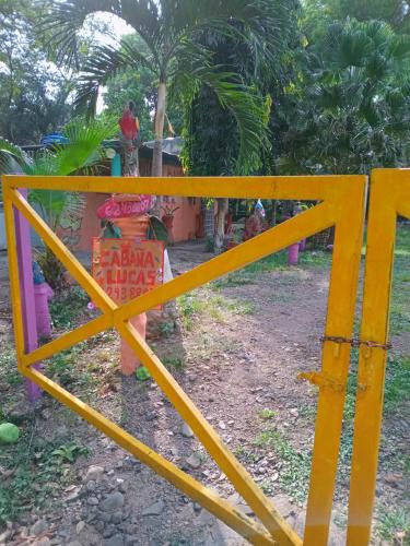 a yellow fence in front of a house with a tree at Cabaña de Lucas in Loma Bonita
