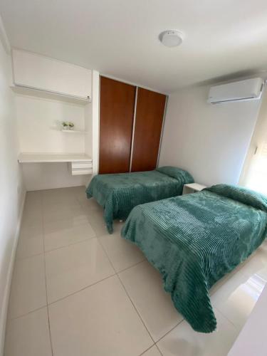 two beds with green comforters in a room at Dpto 9 DE JULIO in Villa María