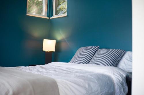 a blue bedroom with a white bed and a lamp at Lakefront retreat close to Microsoft and Bellevue in Redmond
