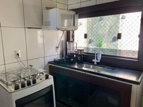 a kitchen with a stove and a sink and a window at Apartamento Vista Praia do Anil in Angra dos Reis