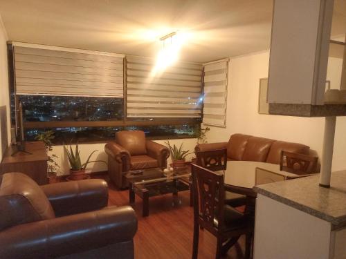 a living room with leather furniture and a window at Acogedor Departamento in Iquique