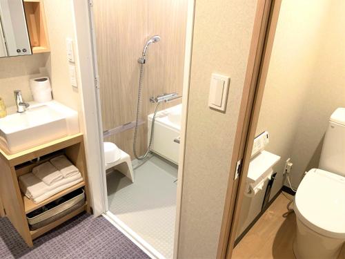 a bathroom with a shower and a toilet and a sink at Henn na Hotel Kanazawa Korimbo in Kanazawa