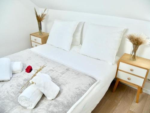 - un lit blanc avec des serviettes et une rose dans l'établissement Haven Home, à Melun