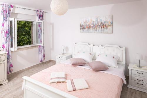 a white bedroom with a large bed with two pillows at Family friendly house with a swimming pool Zastrazisce, Hvar - 23743 in Zastražišće