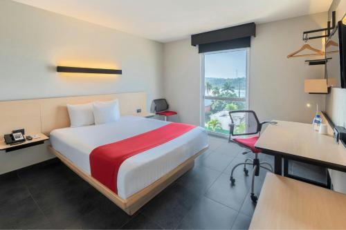 una camera d'albergo con un letto, una scrivania e una finestra di City Express by Marriott Tuxpan a Tuxpan de Rodríguez Cano
