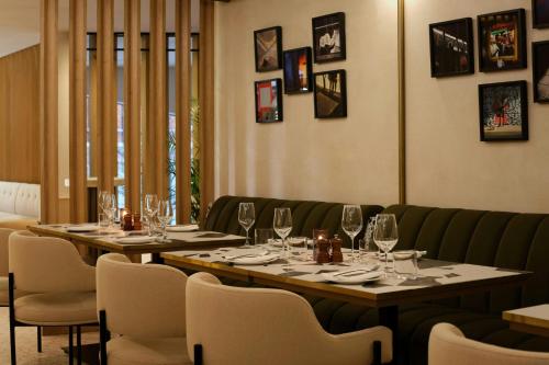 a dining room with two tables and chairs with wine glasses at Montcalm East, Autograph Collection in London