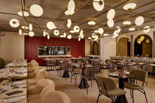 a restaurant with tables and chairs and chandeliers at Montcalm East, Autograph Collection in London
