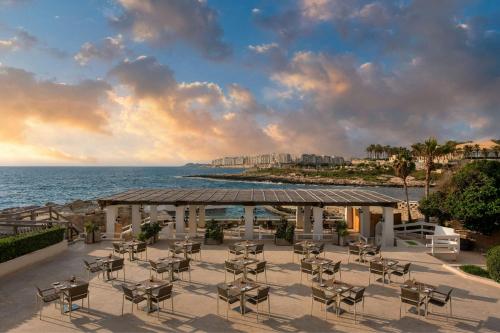 a gazebo with chairs and tables and the ocean at The Westin Dragonara Resort, Malta in St Julian's